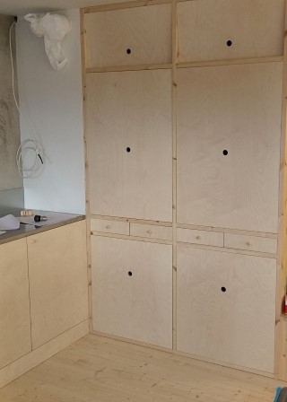 Platsbyggt skafferi av furulimfog och björkplywood med stängda luckor och klaffar